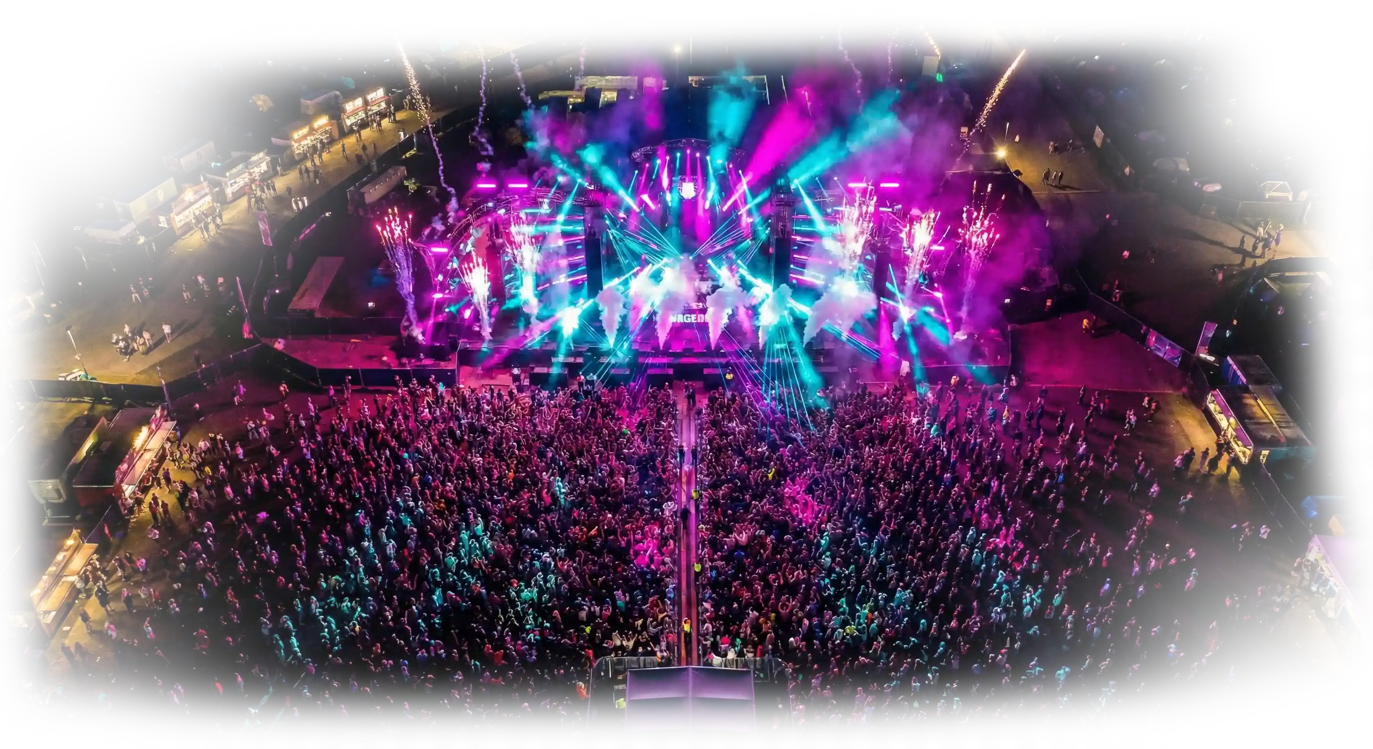 Plano aéreo de un festival nocturno con haces de luz rosas y azules